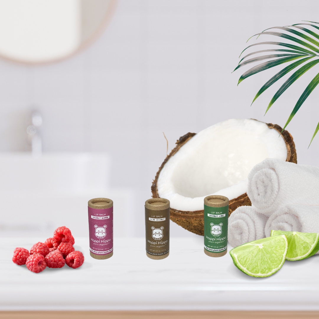 Hippotanicals Coconut Berry, Calm Coconut, and Coconut Lime lip balms in biodegradable kraft push-up tubes, displayed on a white neutral background with a coconut, two lime slices, and a cluster of raspberries in the background for a natural, tropical touch.
